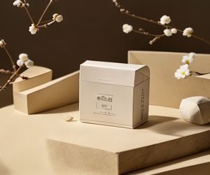 佐山爱品牌产品特写，精致包装置于米色背景之上，体现高端质感与匠心工艺