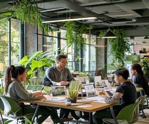 佐山爱团队成员在绿意盎然的办公室内进行头脑风暴，桌上摆放着产品样本与设计图纸，气氛活跃